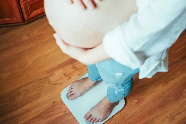 Image of woman weighing herself and experiencing weight gain through pregnancy Gainsborough